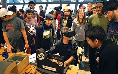 Crowd of students watching one person in front of a laptop with a VR headset on