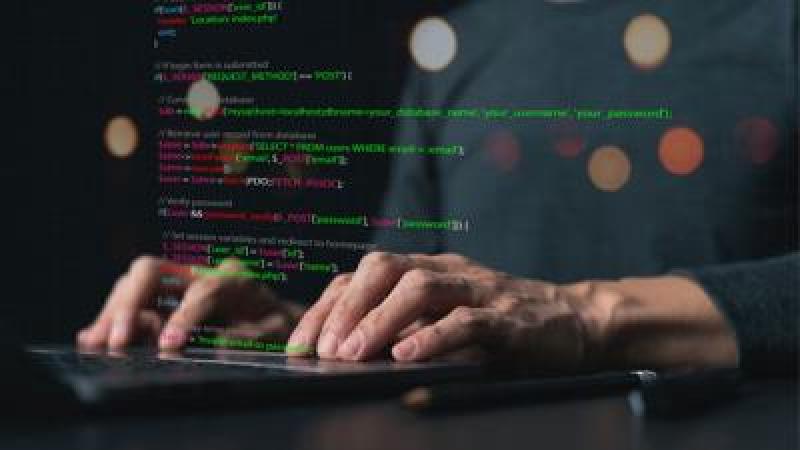 Close up of hands typing on a keyboard with computer code overlay